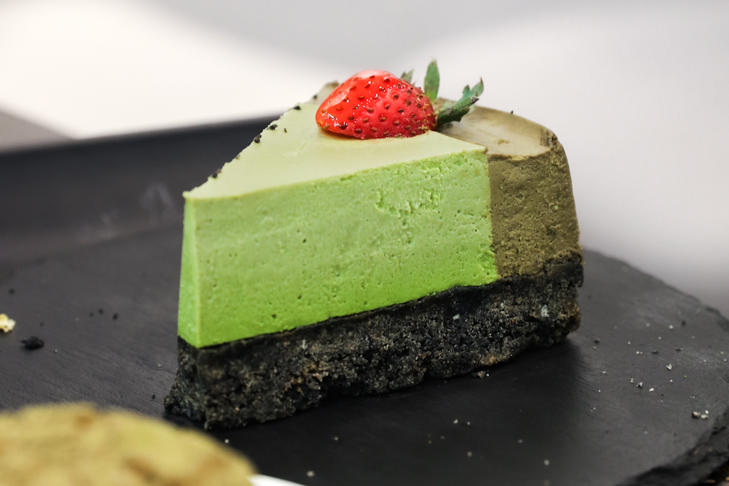 Matcha and Hojicha Cheesecake with black sesame crust and strawberry topping