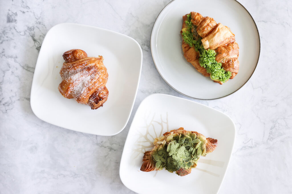 Flat lay of croissants from Percolate. Kaya Croissant, Matcha Almond Croissant and Laksa Fishcake Croissant