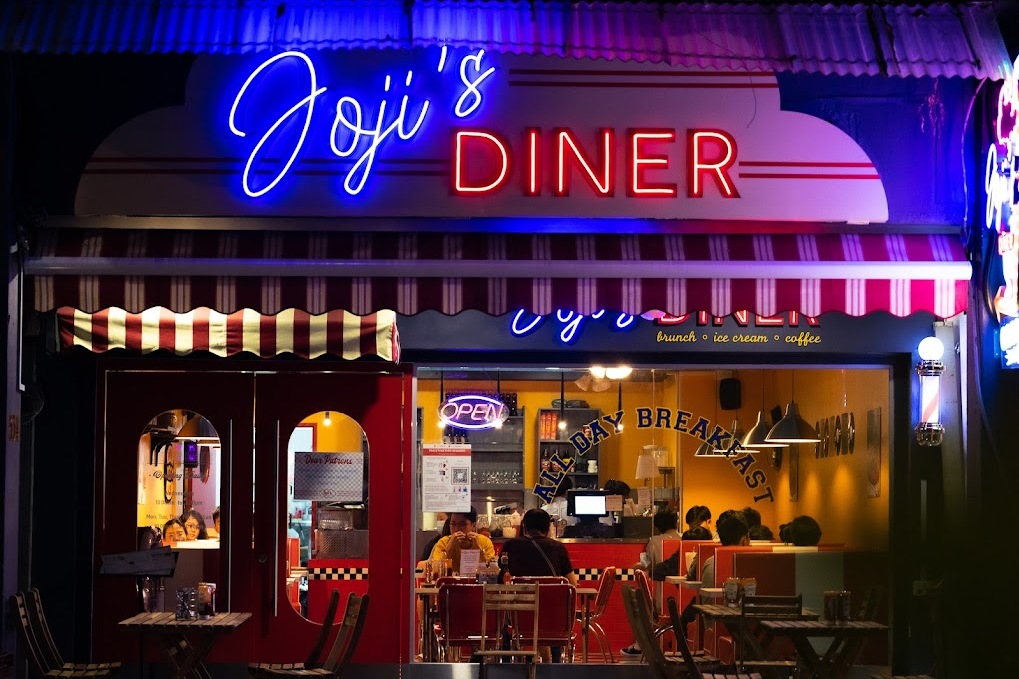 A vibrant neon light sign on the cafe front store., Joji's Diner