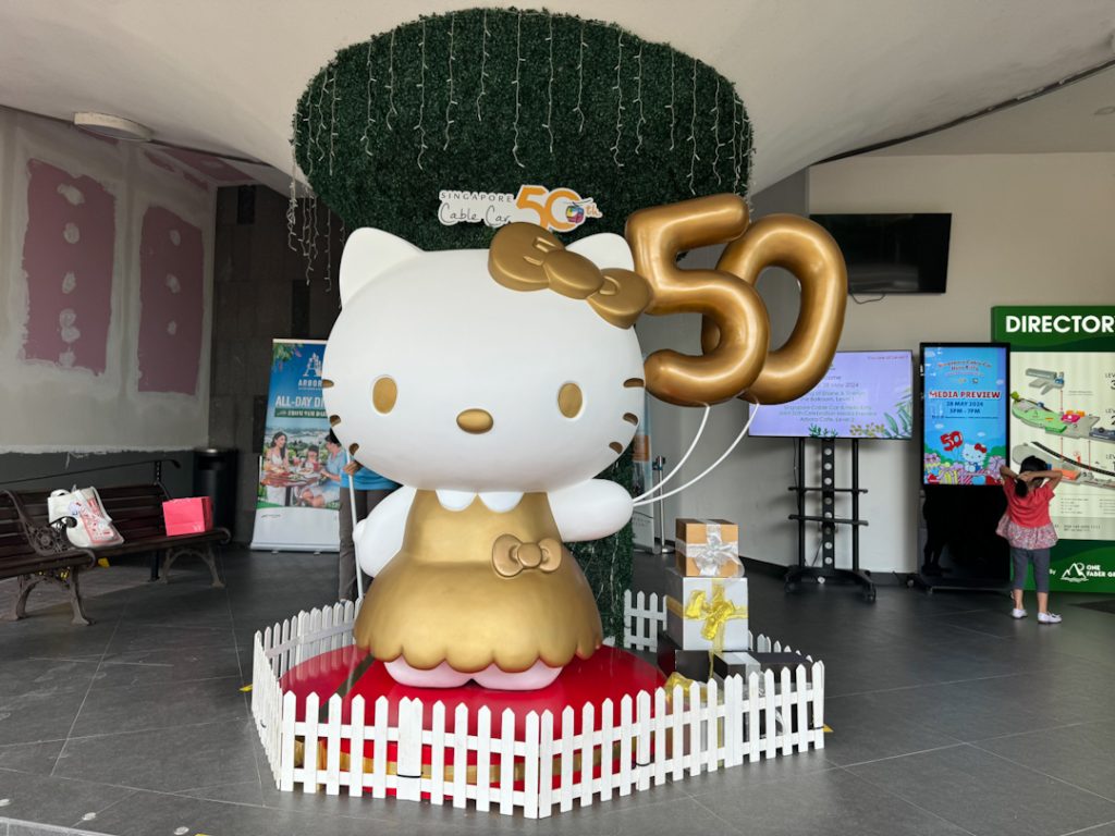 Golden Hello Kitty Mascot holding a "50" balloon to celebrate both brands' anniversaries