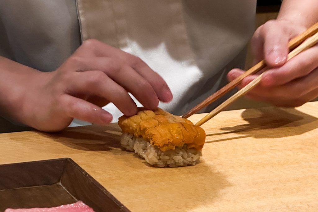 Japanese chef adding bafun uni on sushi rice