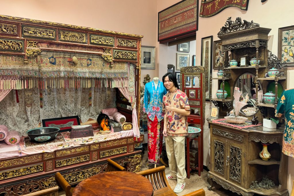 Man wearing baju melayu and posing in front of Peranakan furniture