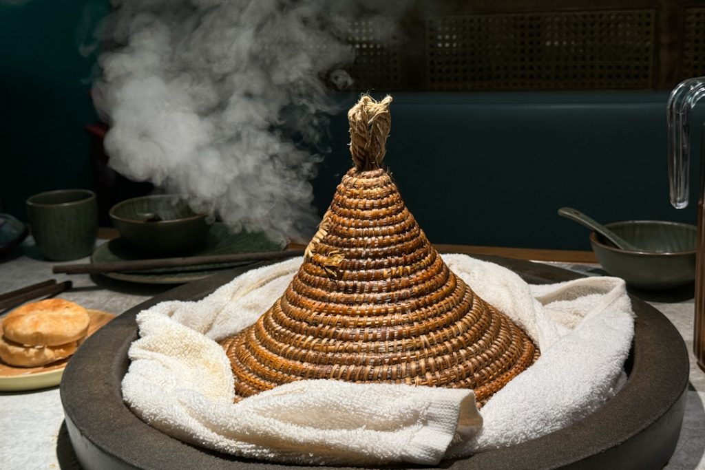 Cooking fish soup in a stone pot and straw hat lid